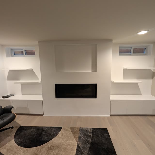 Custom white built-in shelves and cabinetry framing a living-room fireplace